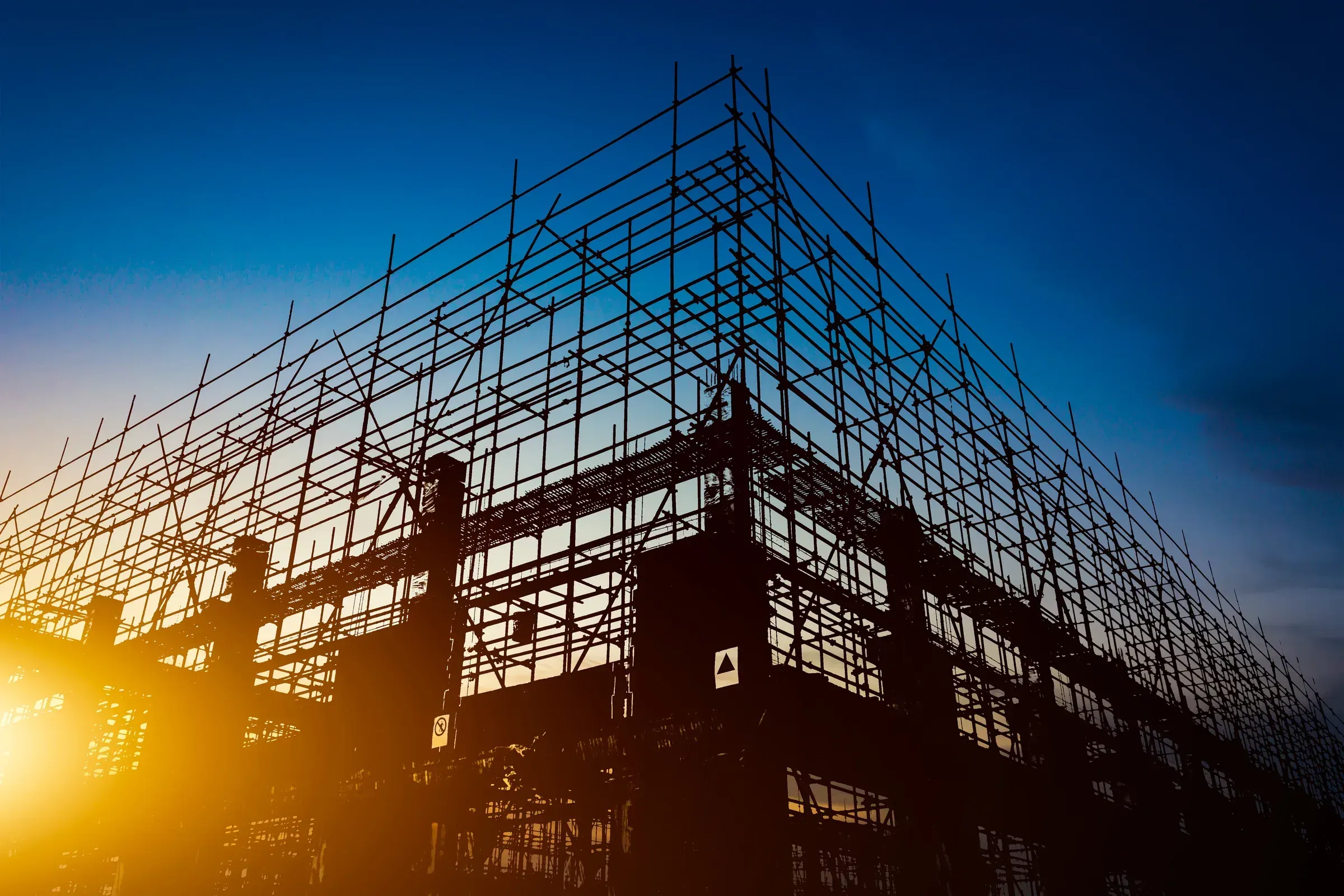 Construction site at sunset with crane silhouettes